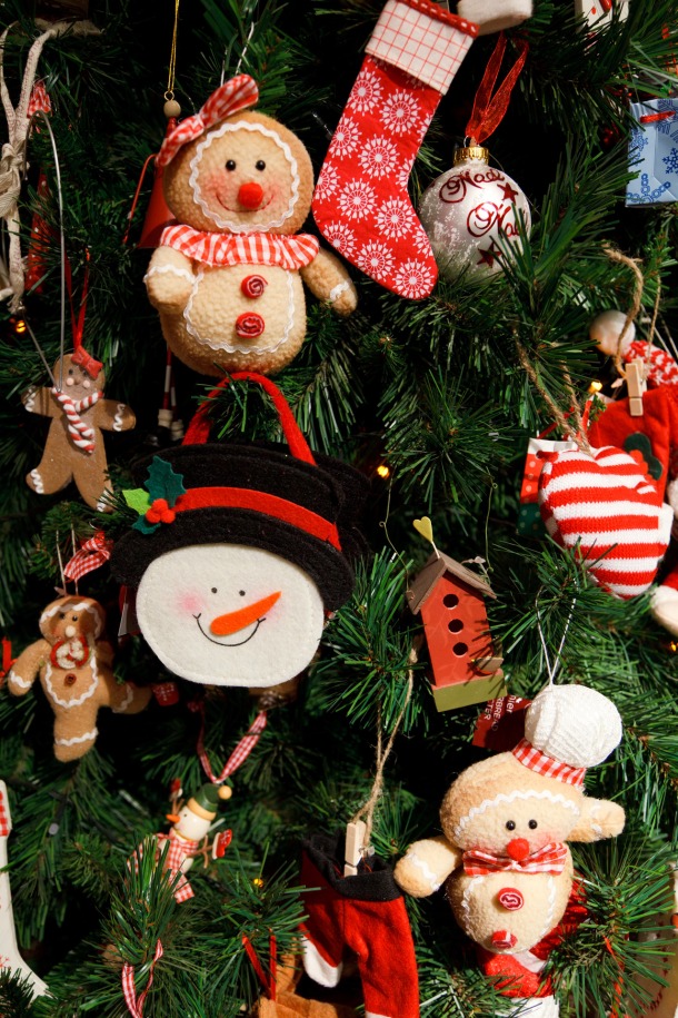Ornaments on Christmas tree including snowman, gingerbread, red birdhouse & more